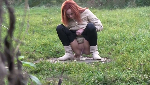 Kinky shameless redhead squats down to piss outdoors on the grass porn pics